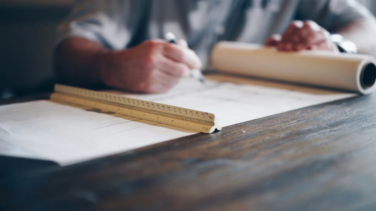 Plans de terrain déroulés sur une table en bois avec un réglet d'architecte
